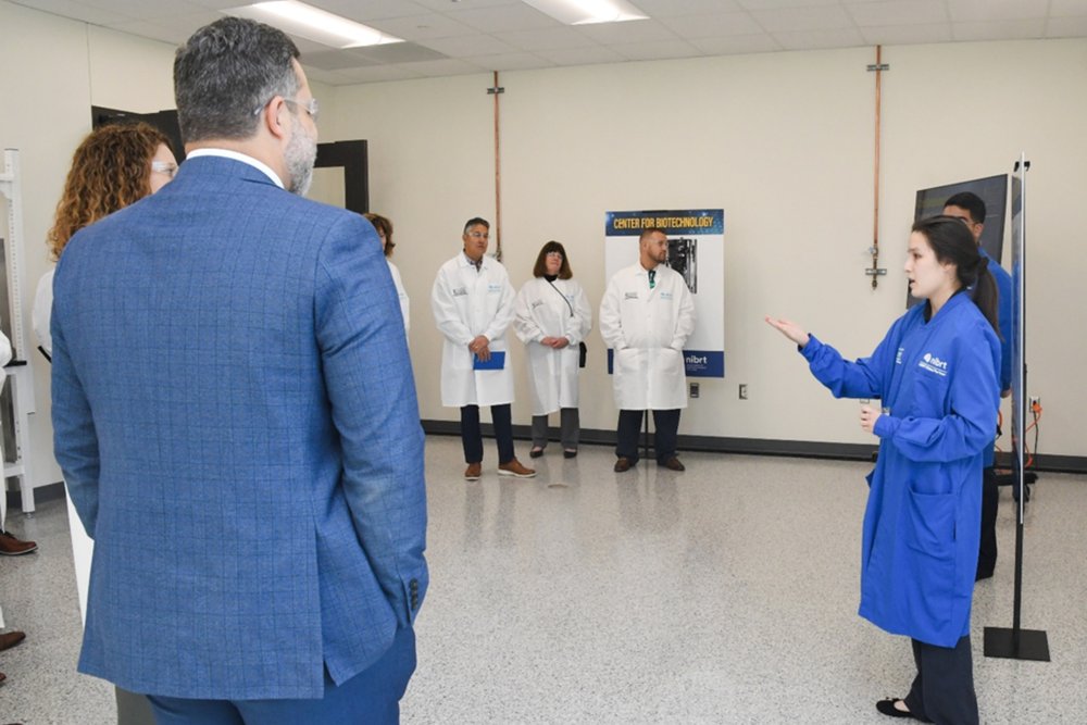 Students in blue lab coats address a crowd during their presentation of the centre