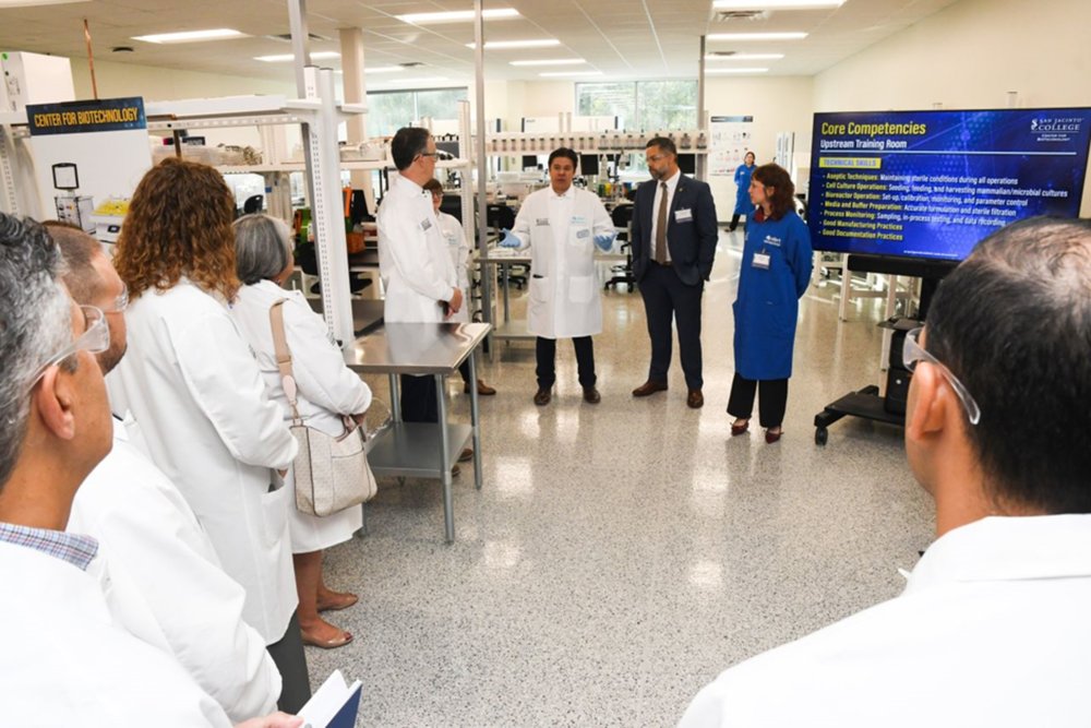 A group of people in lab coats watch a presentation
