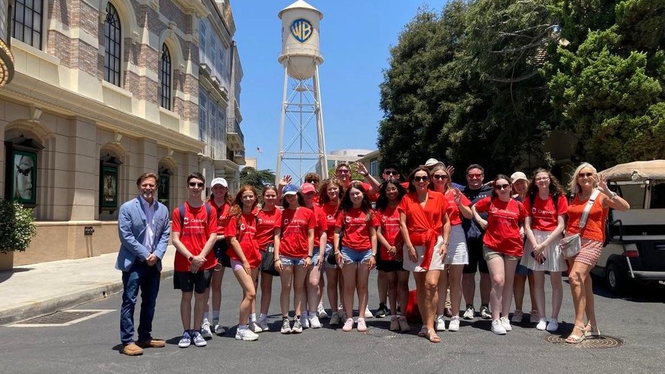 Group photo of students in matching red tshirts with the Warner Brothers tower in the background