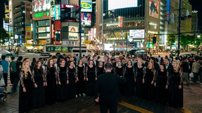 Large choir all dressed in black standing in a semi circle