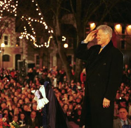 on man in an overcoat saluting to a large crowd at night time