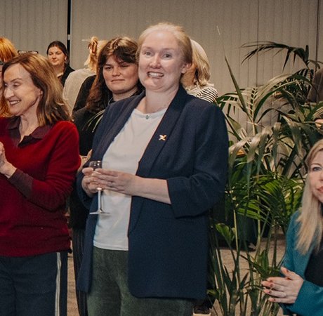 Woman in audience standing listening to speakers