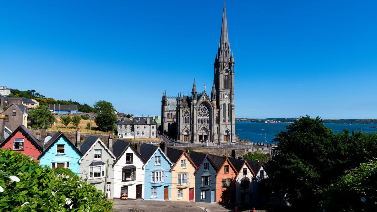 Colourful houses lining a hill with a Cathedral and the sea visible in the background
