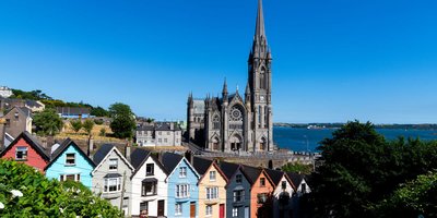 Colourful houses lining a hill with a Cathedral and the sea visible in the background