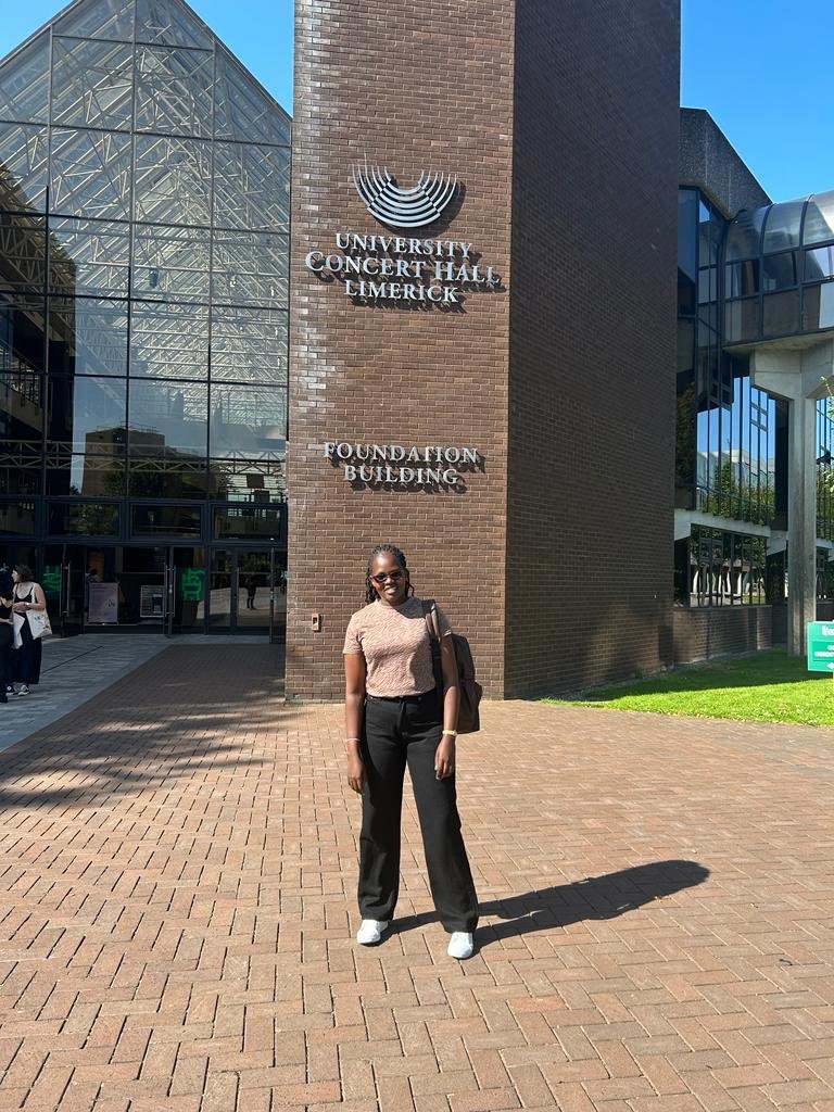 Consolata standing in front of the university entrance