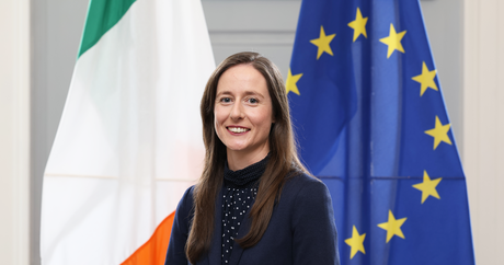 Consul General Claire Fitzgiboon standing in front of the EU and Irish flags.