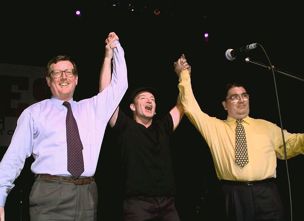 three men holding hands and raising them up triumphantly