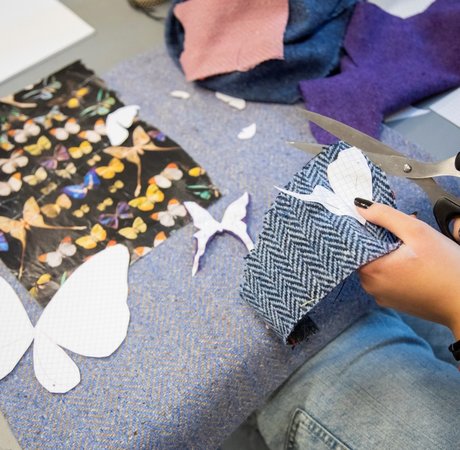 Close up of students' hands cutting up tweed for their projects