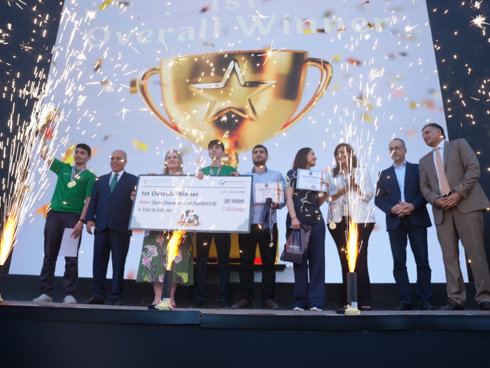 group of young people holding a plaque with backdrop of trophy in background and confetti falling