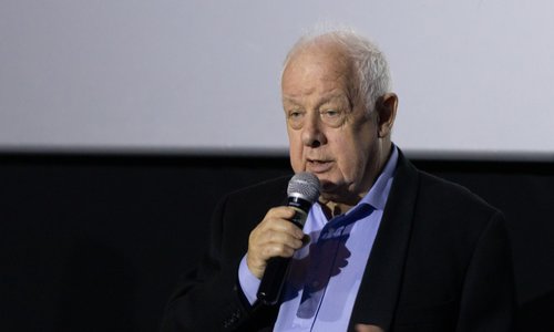 Irish filmmaker Jim Sheridan holding a microphone on a stage