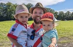 Dónall Ó Dubhghaill holding his two children, all wearing GAA jerseys