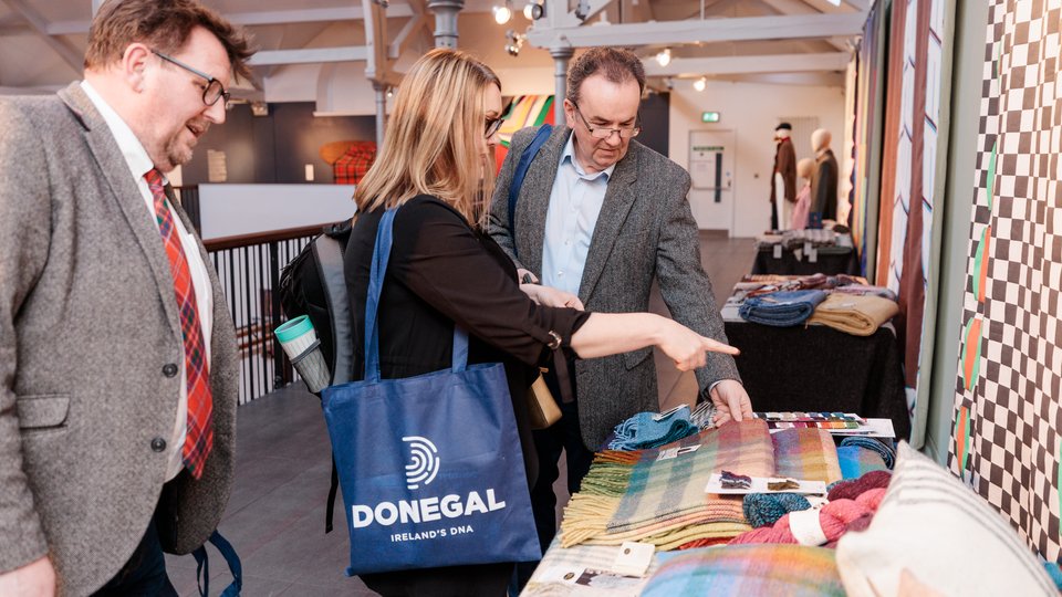 People talking beside tweed garments