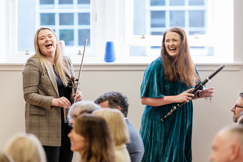 two women laughing with musical instruments in their hands