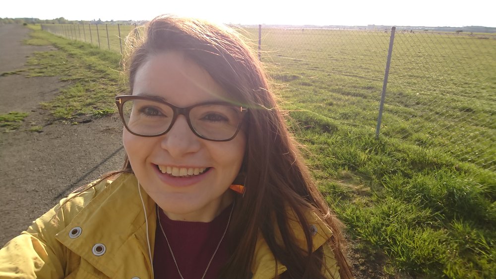 A picture of Dr Claire Murray standing in front of a field on a bright day