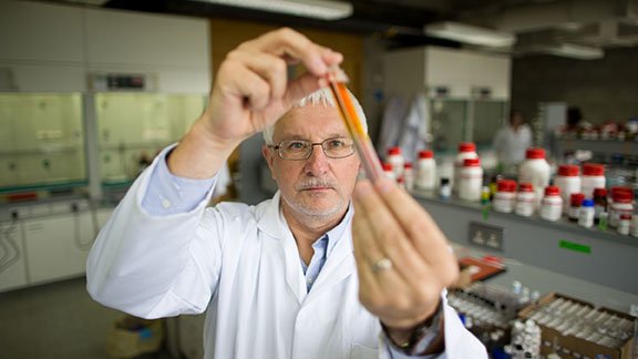 Dr Mike Zaworotko Bernal wears a white lab coat and holds a test tube to the light examining it
