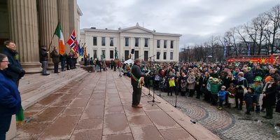 Large group of people outside in a square at a formal event with national flags