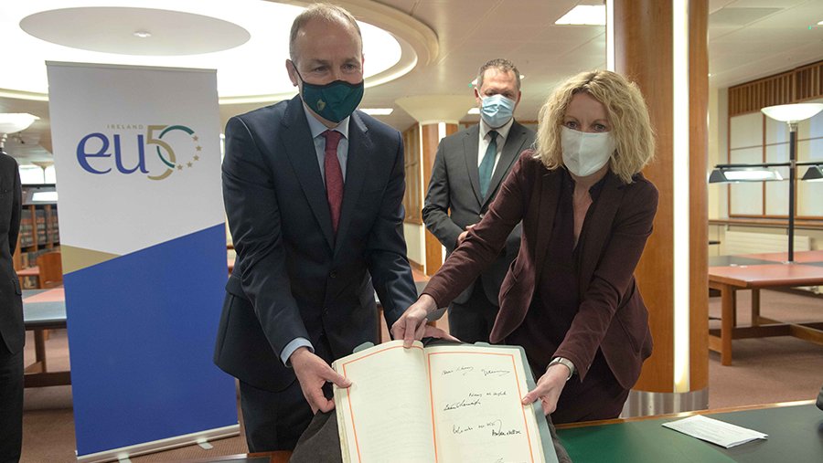 a man and a woman holding a book, wearing protective masks
