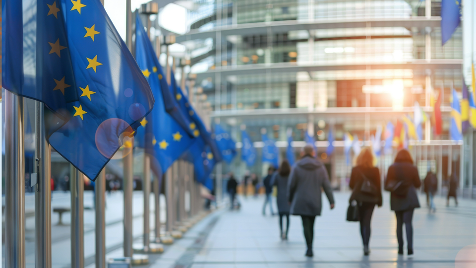 EU flags at modern office building with people walking to work