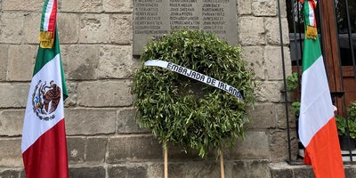 Irish and Mexican flags surrounding a wreath with an Embassy of Ireland banner across it.