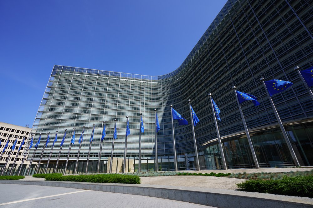 European Commission building with a row of EU flags flying outside