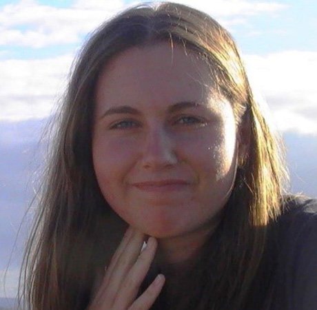 a young woman with long brown hair holding her hand to her chin and wearing a beaded bracelet