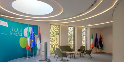 The Hamilton Room, a room within the Irish Pavilion at Expo, featuring a stage with podium, Irish, EU and UAE flags and a meeting space.
