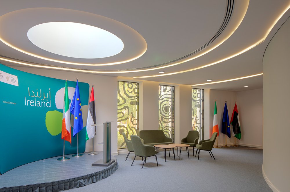 The Hamilton Room, a room within the Irish Pavilion at Expo, featuring a stage with podium, Irish, EU and UAE flags and a meeting space.