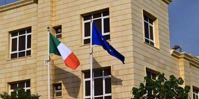 View of the exterior of the Embassy building with the Irish and EU flags flying on flag poles.