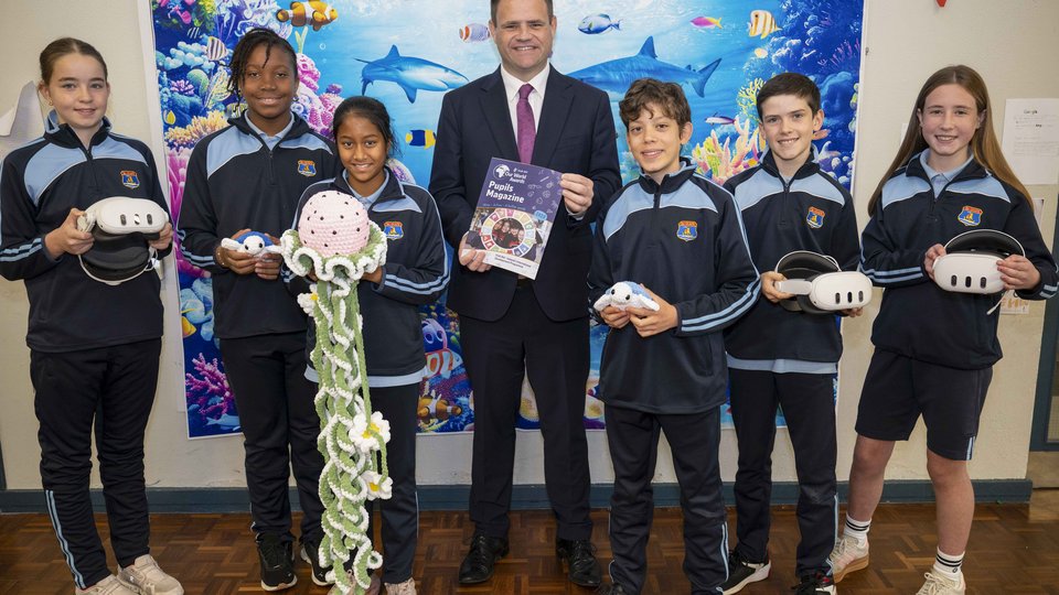 Smiling man in suit with children standing beside him.