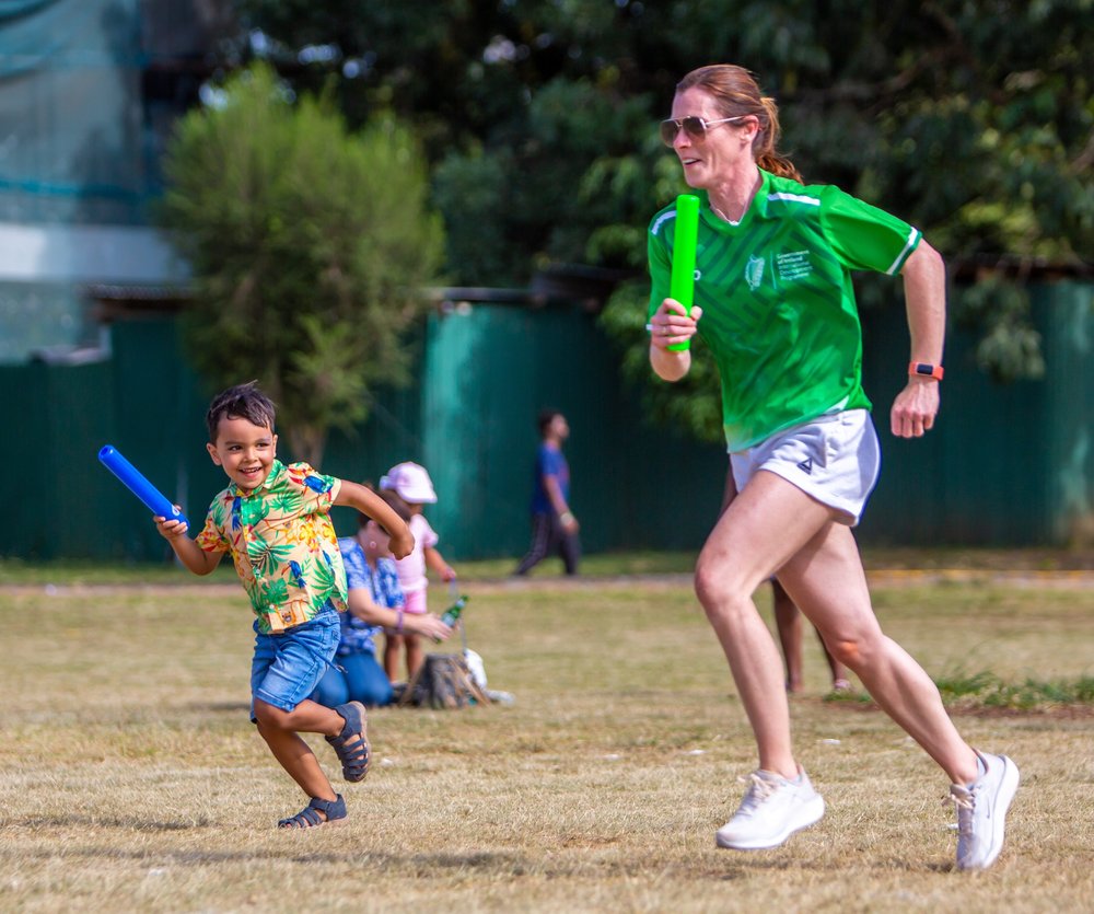Karen Shinkins running a relay holding a baton alongside a small boy