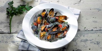 bowl of mussels in a cream sauce on a rustic table