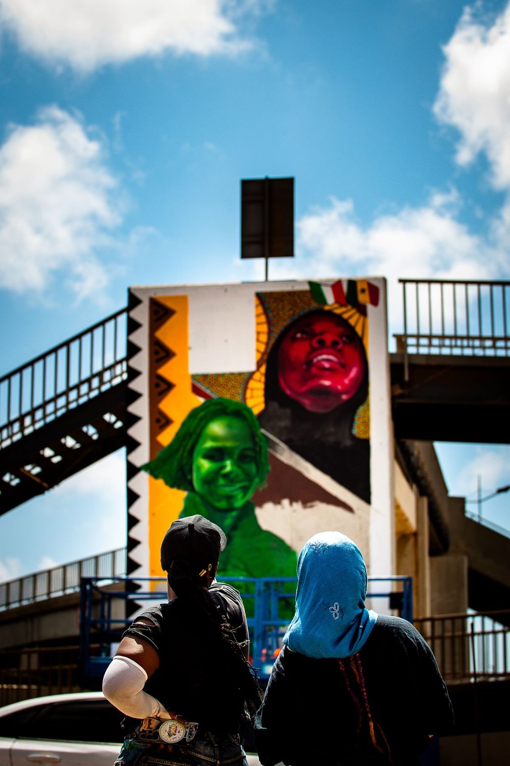 Two women looking up at the mural of two female sports-stars they have painted