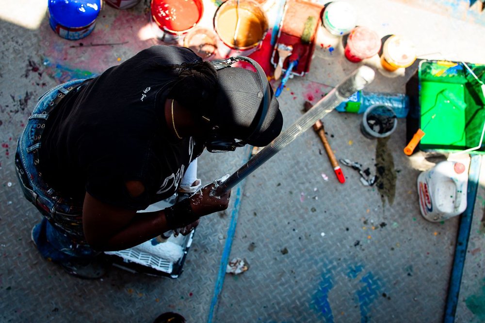 Artist crouching down amongst their paint supplies