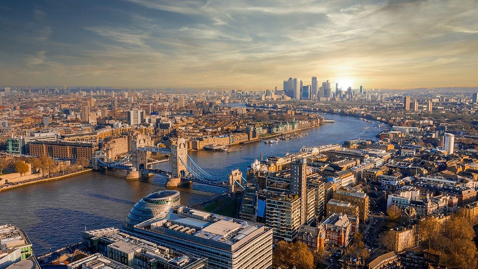 An aerial photo of London overlooking the Thames with a sunrise in the background