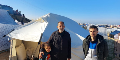 Family in Gaza standing at their Irish Aid tent