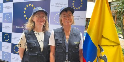 Geraldine and Claire O'Neill standing beside an Ecuador Flag