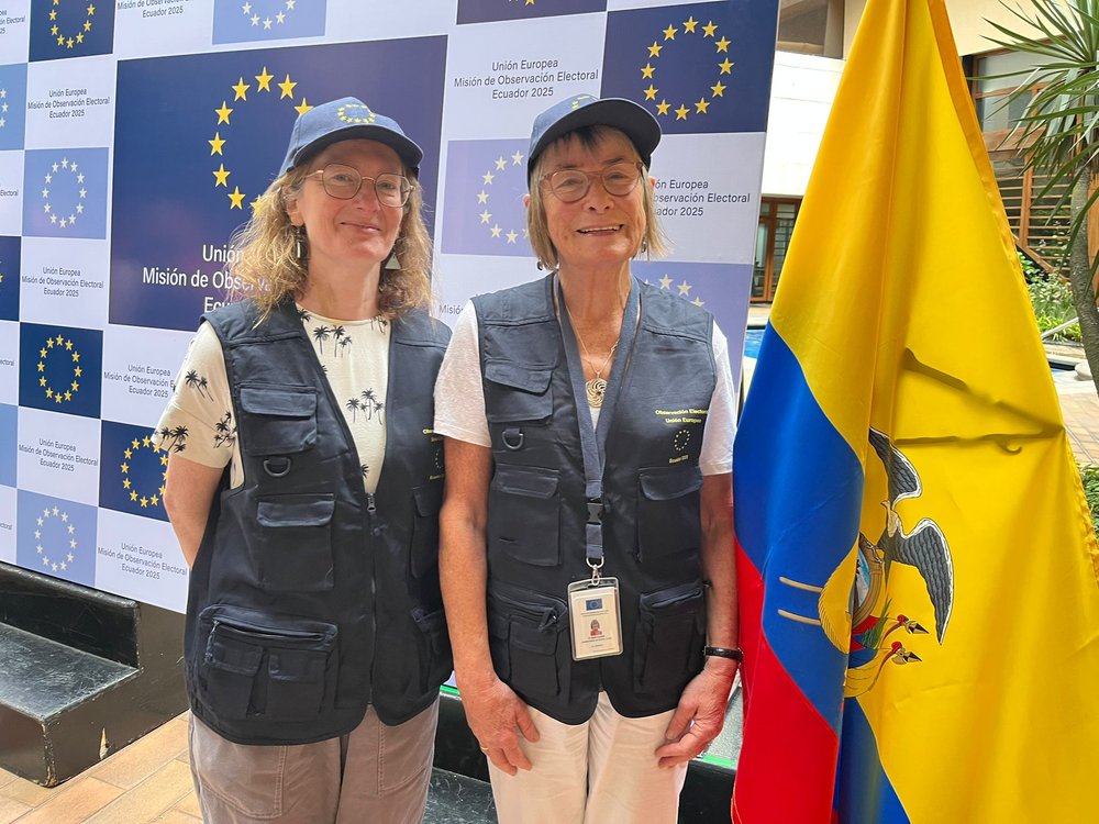 Geraldine and Claire O'Neill standing beside an Ecuador Flag