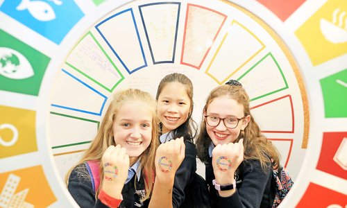 Three young girls with Global Goals stamps on their hands.