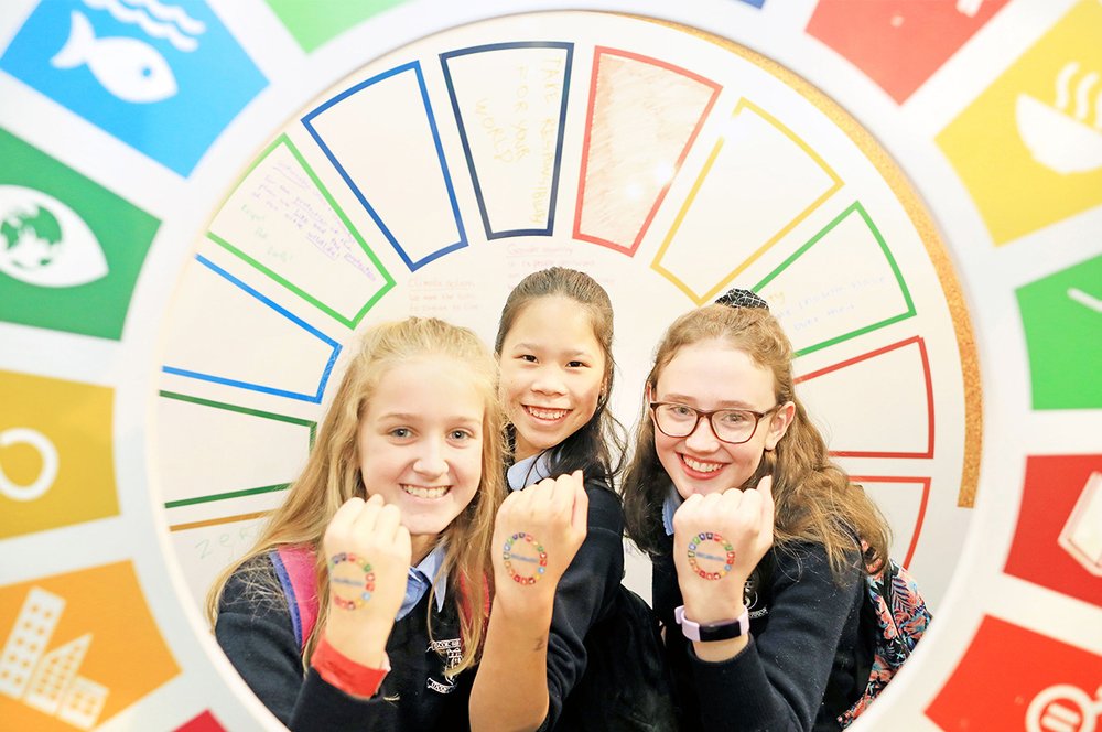 Three young girls with Global Goals stamps on their hands.