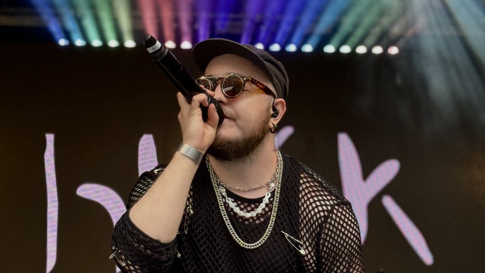 Person singing in front of rainbow lights
