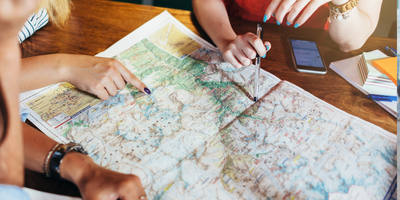 Three people pointing at map to plan a journey