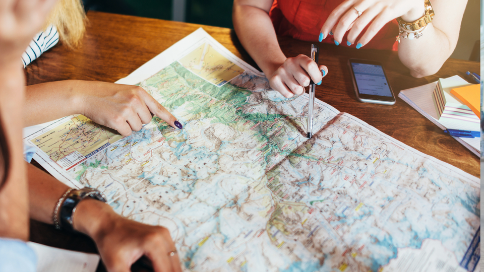 A group of friends planning their trip by pointing at a map