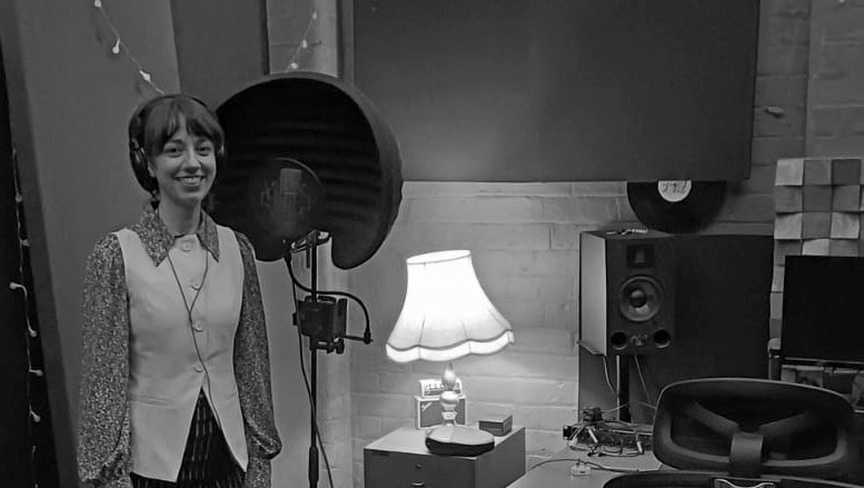 Woman standing beside a mic in a studio