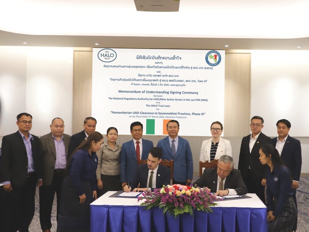 people standing along behind two people signing an agreement