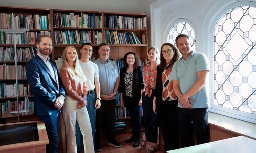A group of people smiling in front of a bookcase