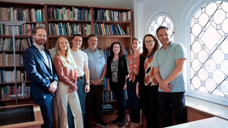 A group of people smiling in front of a bookcase