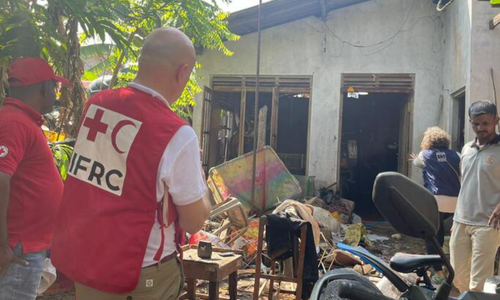 IFRC workers work through wreckage outside a house
