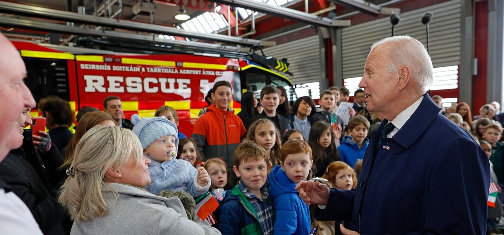 Crowd of people of mixed ages in front of a fire engine with President Biden addressing them