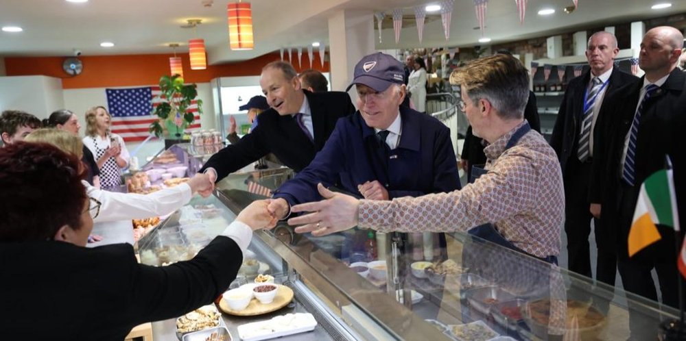 three people leaning over a food counter in a restaurant to shake hands