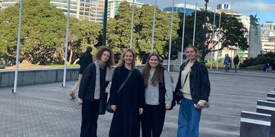 Four women standing under a rainbow